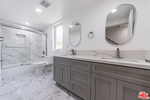 a spacious bathroom with a double vanity sink double mirror bathtub and toilet