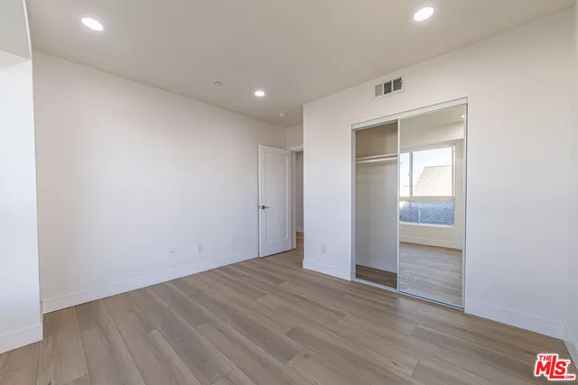 an empty room with wooden floor & closet