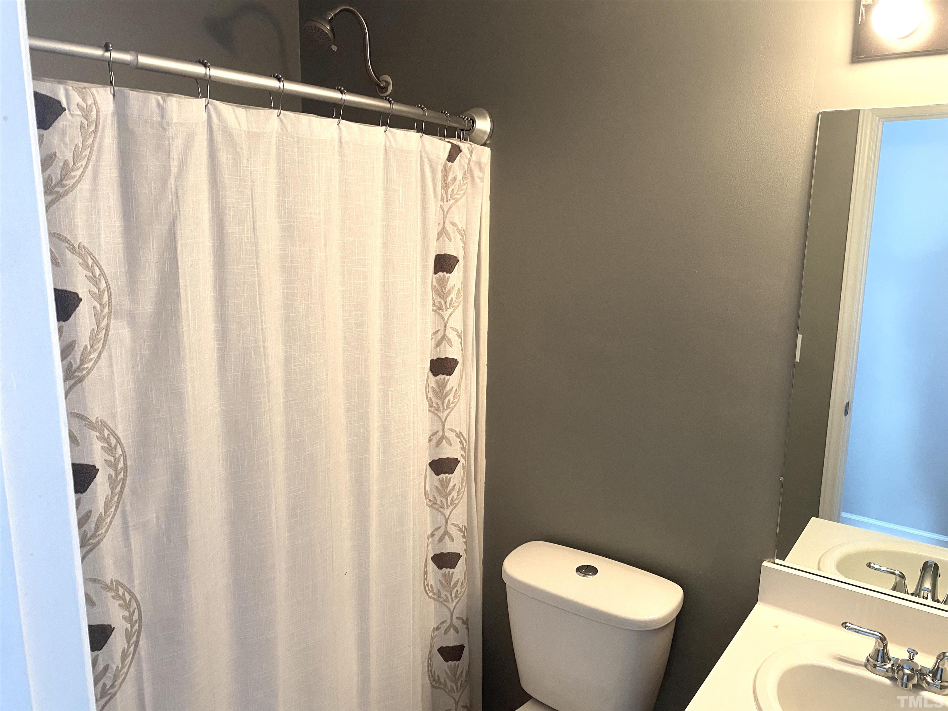 5104 Gable Ridge Drive Durham, NC 27713 - Photo 9 of 16 a white toilet sitting next to a shower curtain