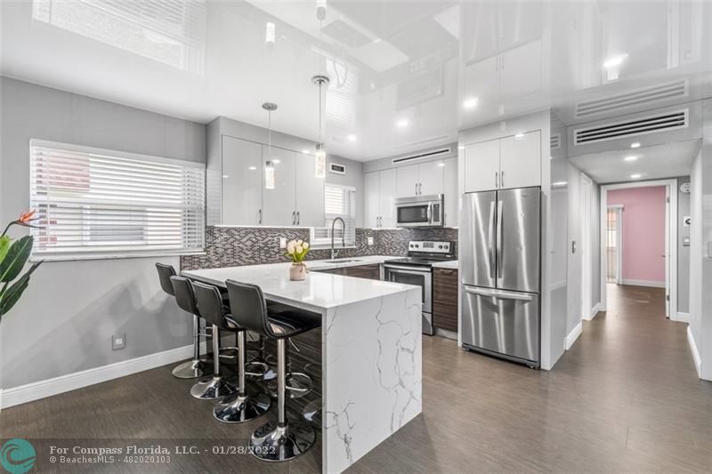 a kitchen with stainless steel appliances a dining table chairs and a refrigerator