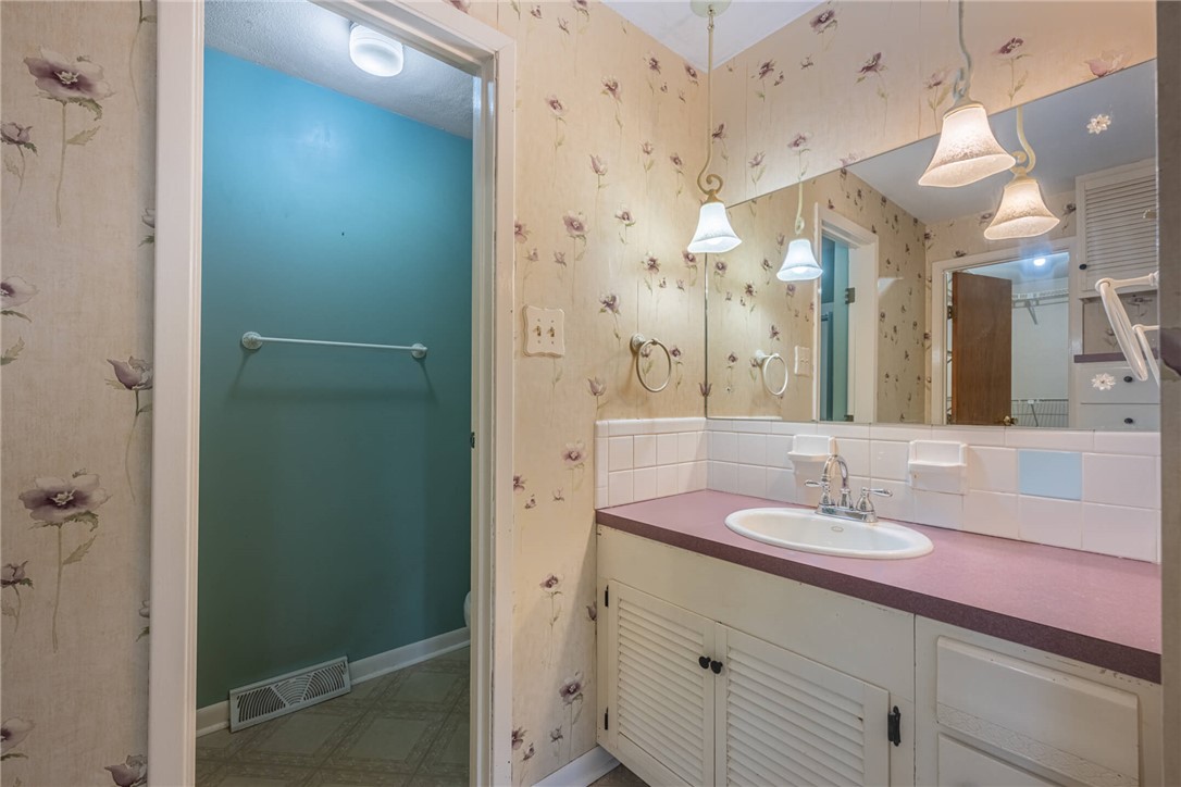6300 Carnation Road Dayton, OH 45449 - Photo 18 of 35 This classic bathroom features a vanity with a sink, large mirror, and tiled backsplash.