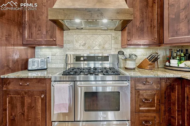 a kitchen with stainless steel appliances granite countertop a stove a sink and a refrigerator with wooden floors
