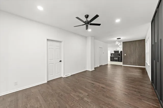 a view of an empty room with wooden floor and a ceiling fan