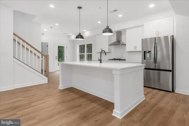 a large kitchen with stainless steel appliances kitchen island a large counter top and wooden floors