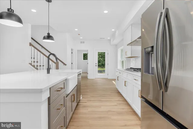 a kitchen with kitchen island a counter top space a sink a refrigerator and a view of living room
