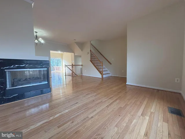 a view of an empty room with wooden floor fireplace and a window