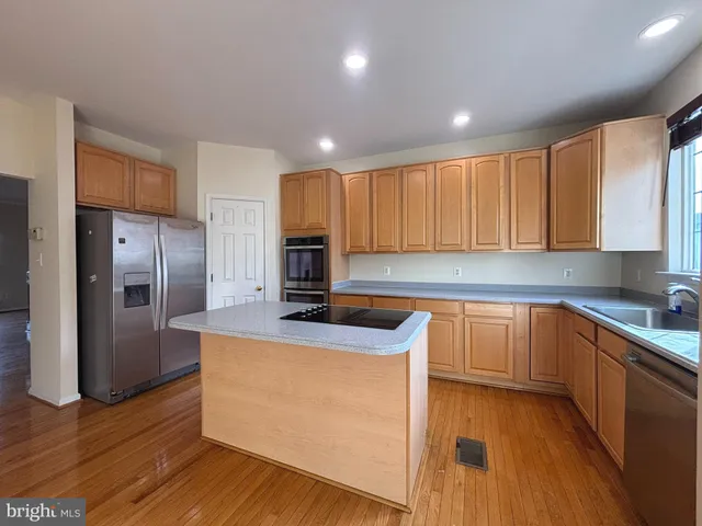 a kitchen with stainless steel appliances granite countertop a refrigerator a sink dishwasher a stove with wooden floors and cabinets