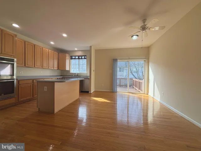 a kitchen with stainless steel appliances granite countertop a stove top oven a sink dishwasher a refrigerator and white cabinets with wooden floor