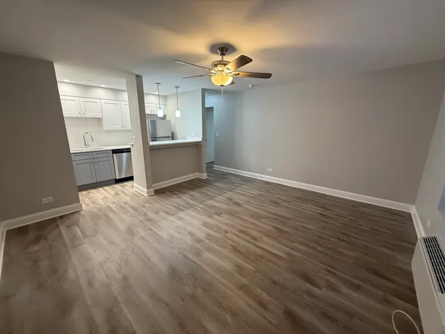 a view of an empty room with a window and wooden floor