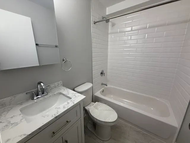 a bathroom with a granite countertop sink toilet and shower