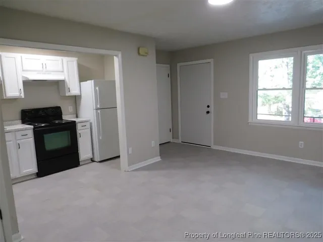 a kitchen with white cabinets and refrigerator
