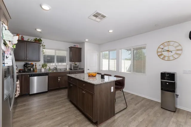 a kitchen with stainless steel appliances granite countertop a stove a sink a refrigerator and wooden floor