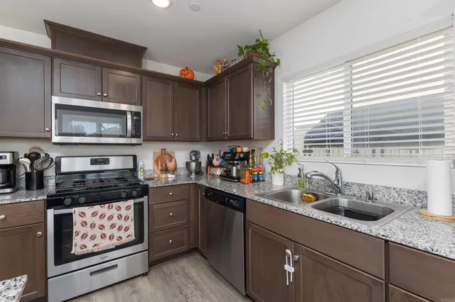 a kitchen with stainless steel appliances granite countertop a sink a stove a microwave cabinets and a window