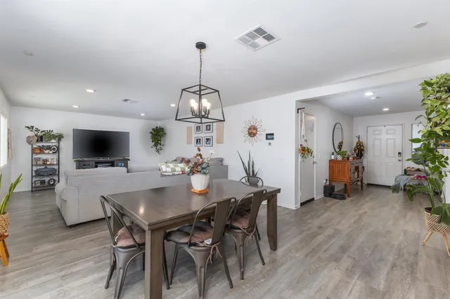 a view of a dining room and livingroom with furniture wooden floor a chandelier