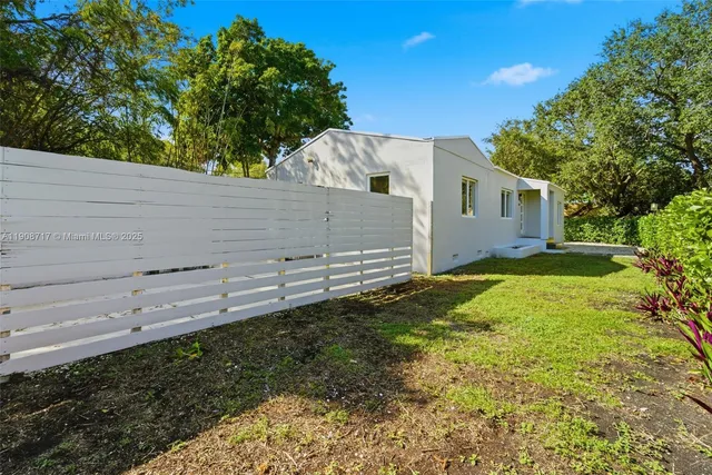 a view of a backyard with plants and large tree