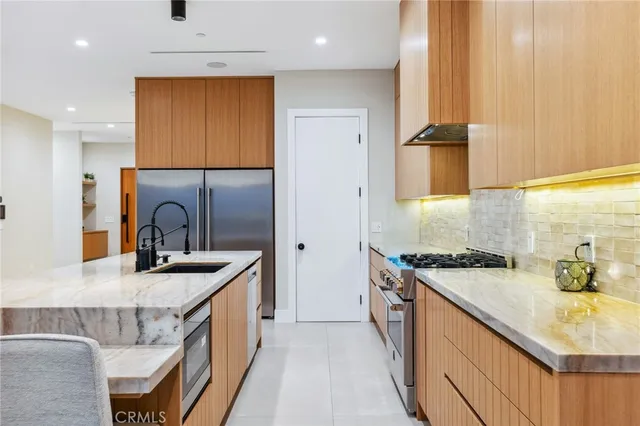 a kitchen with stainless steel appliances granite countertop a sink a stove and a refrigerator