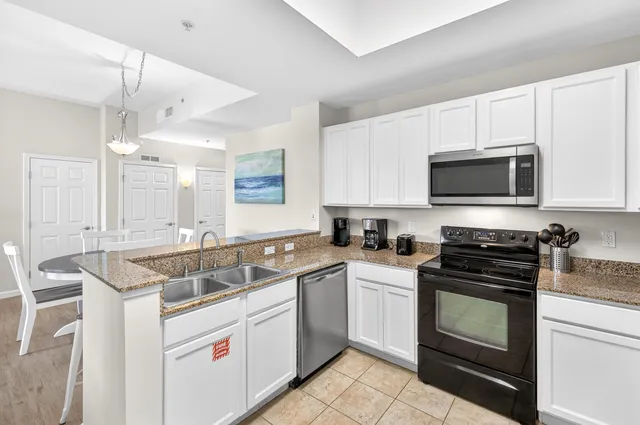 a kitchen with granite countertop white cabinets and stainless steel appliances