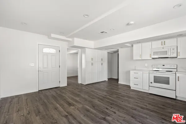 a view of a kitchen with wooden floors and white cabinets