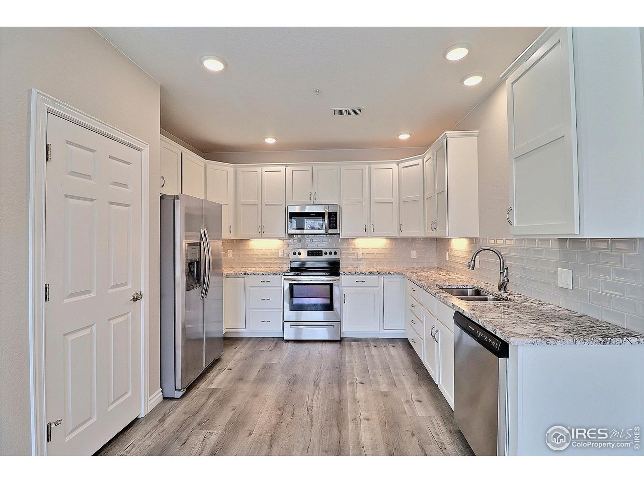 4672 West 20th Road, Unit 525 Greeley, CO 80634 - Photo 12 of 35 a kitchen with stainless steel appliances granite countertop a refrigerator oven a sink dishwasher and a stove with wooden floor