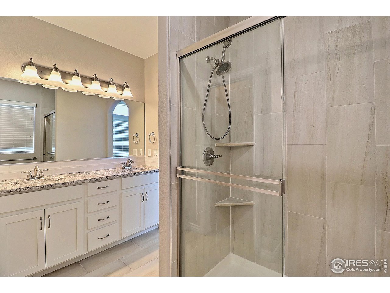 4672 West 20th Road, Unit 525 Greeley, CO 80634 - Photo 23 of 35 a bathroom with a granite countertop sink a mirror a vanity and a shower