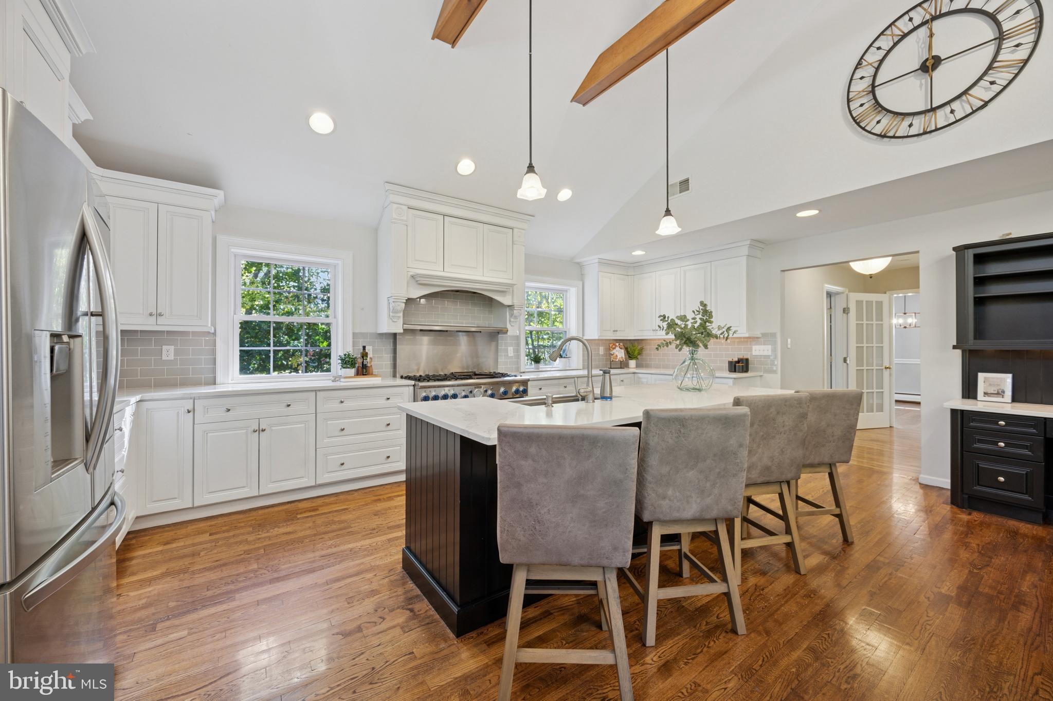 570 Fletcher Road Wayne, PA 19087 - Photo 32 of 54 a kitchen with stainless steel appliances granite countertop a stove a refrigerator a kitchen island with a dining table and chairs with wooden floor