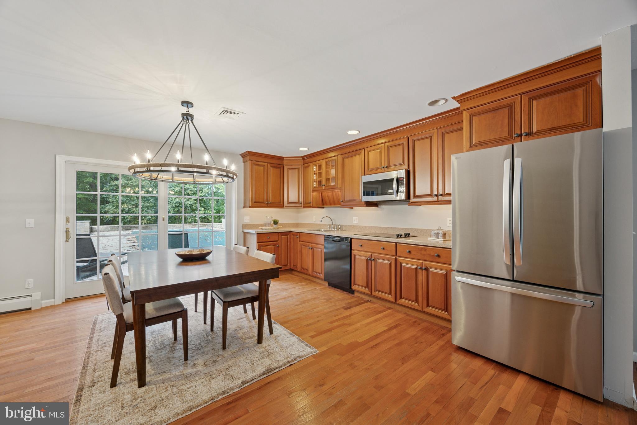 570 Fletcher Road Wayne, PA 19087 - Photo 51 of 54 a kitchen with stainless steel appliances granite countertop a refrigerator a stove a sink dishwasher a dining table and chairs with wooden floor