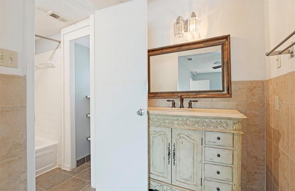 5808 Harvest Hill Road Dallas, TX 75230 - Photo 16 of 18 Bathroom vanity with an ornate wood-framed mirror, dual-handle faucet, and carved cabinet with integrated drawers