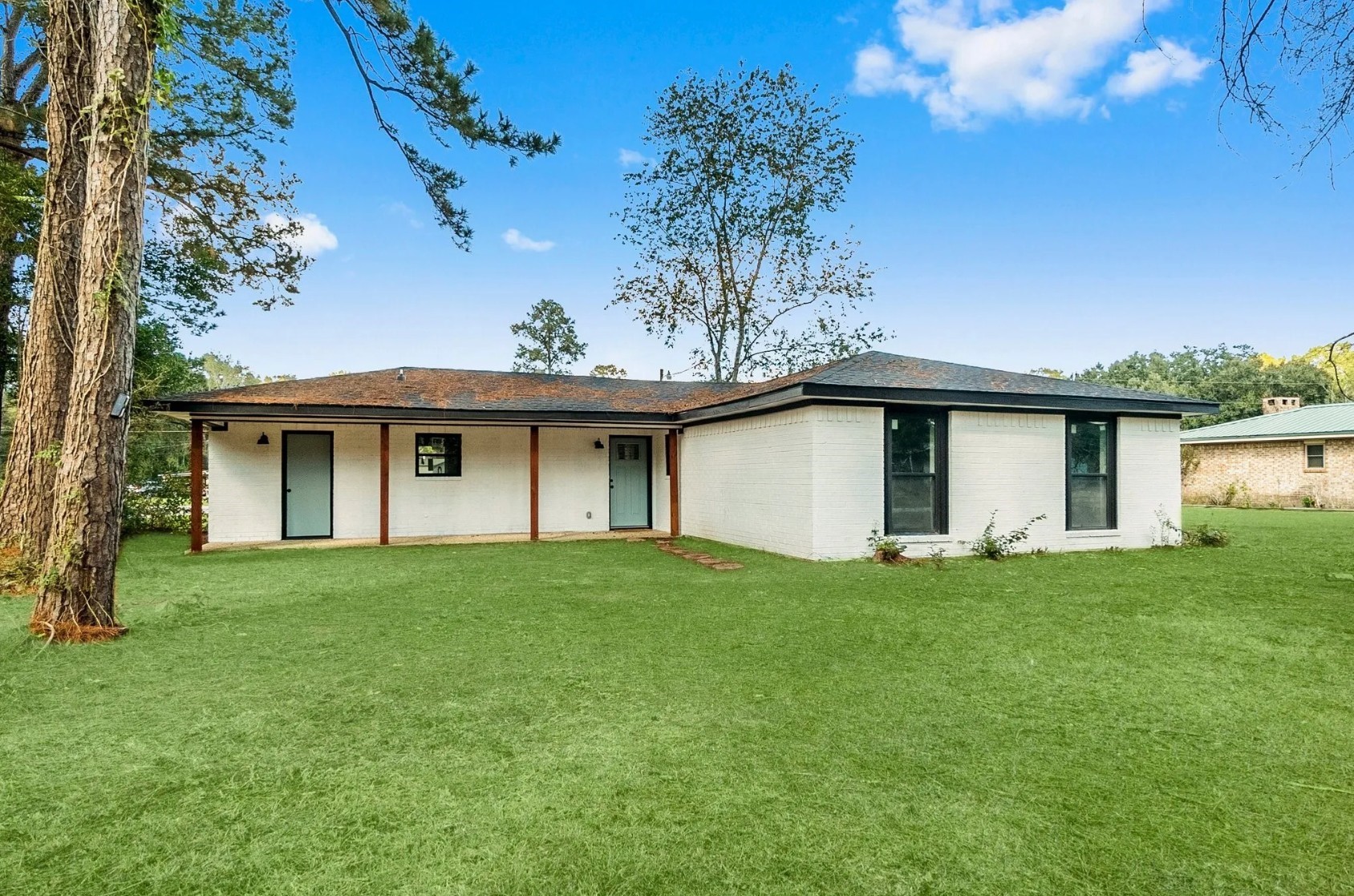 749 County Road 774 Buna, TX 77612 - Photo 2 of 9 Discover this charming home featuring a clean, modern facade with fresh white brick and sleek black trim, nestled in a serene, expansive yard perfect for outdoor enjoyment.