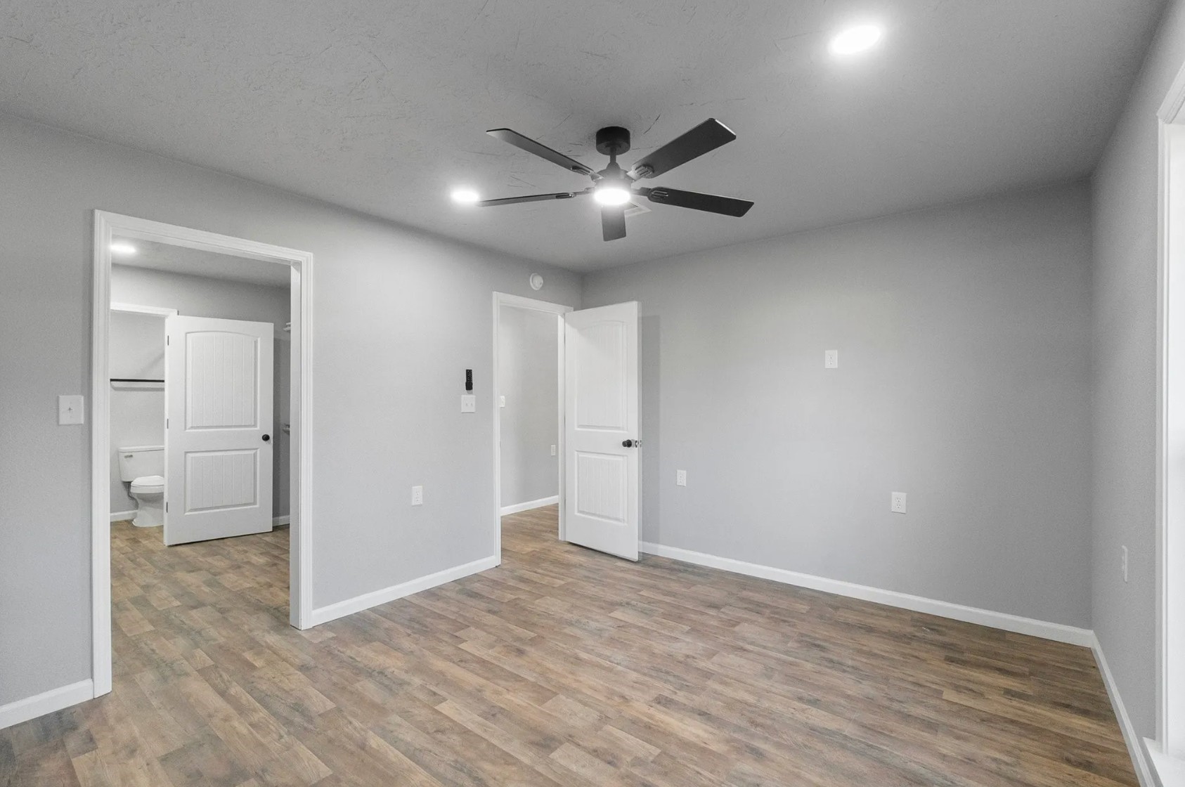 749 County Road 774 Buna, TX 77612 - Photo 5 of 9 This inviting bedroom features sleek hardwood-looking floors, modern recessed lighting, and a convenient en-suite bathroom, creating a perfect blend of comfort and style.