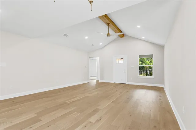 an empty room with wooden floor cabinet and windows