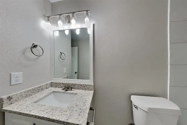 a bathroom with a granite countertop sink a toilet and mirror