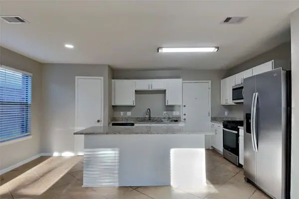 a kitchen with kitchen island a counter top space cabinets and stainless steel appliances