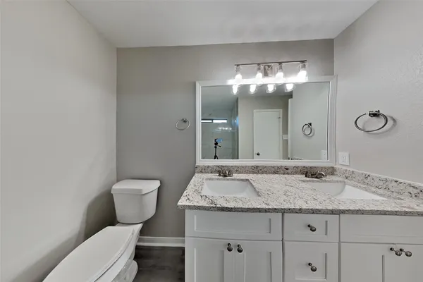 a bathroom with a granite countertop toilet sink and mirror