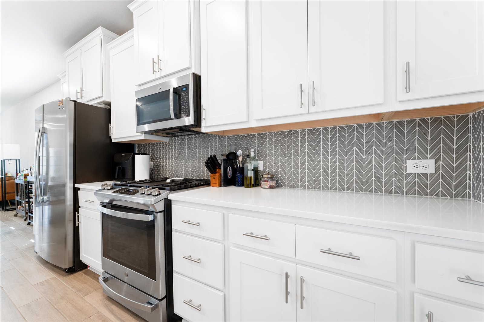 4607 Sweet Annie Path Austin, TX 78723 - Photo 11 of 29 Kitchen featuring stainless steel appliances, a breakfast bar, white cabinetry, light wood-style floors, and a kitchen island with sink