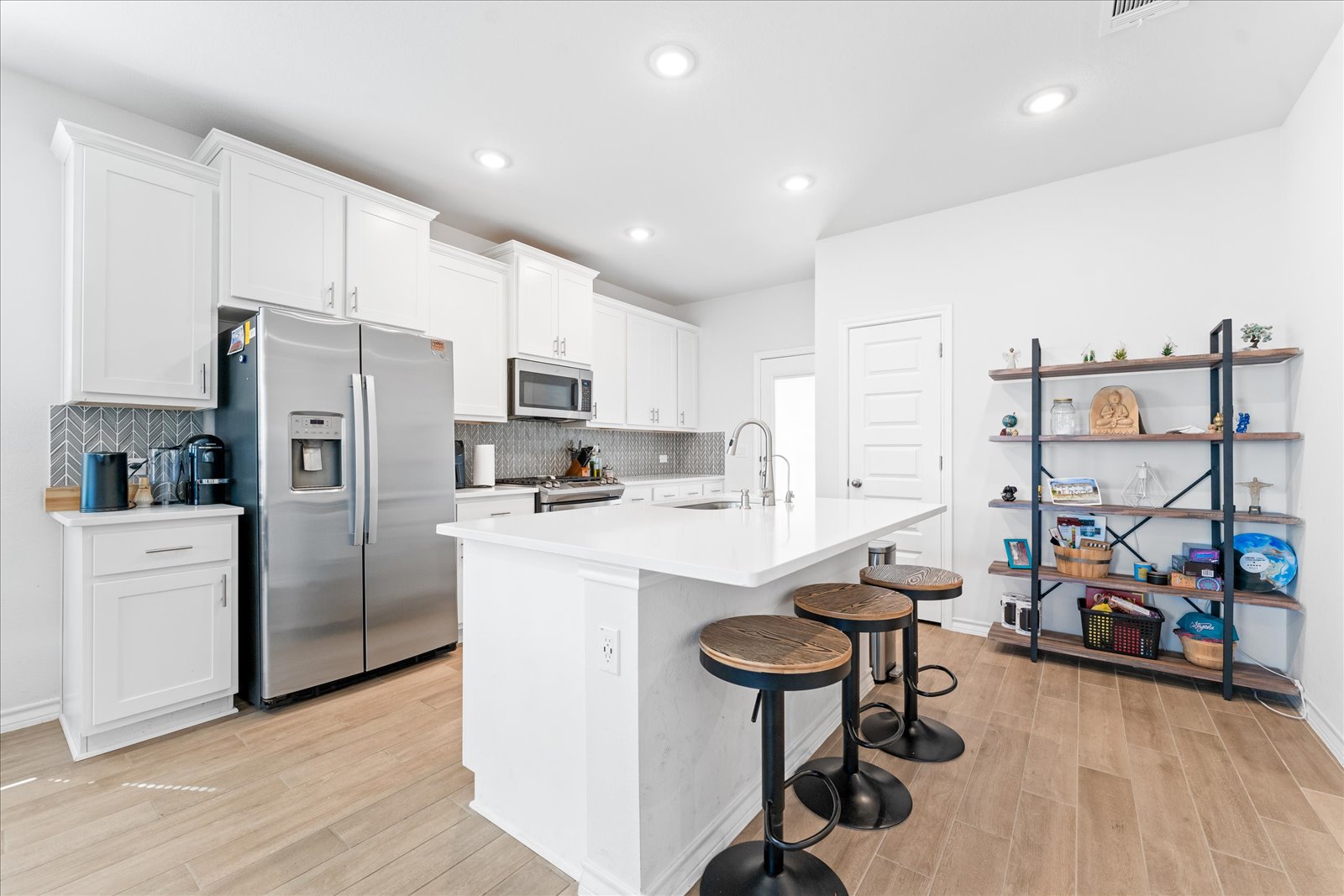 4607 Sweet Annie Path Austin, TX 78723 - Photo 6 of 29 Kitchen featuring stainless steel appliances, a breakfast bar, white cabinetry, light wood-style floors, and a kitchen island with sink