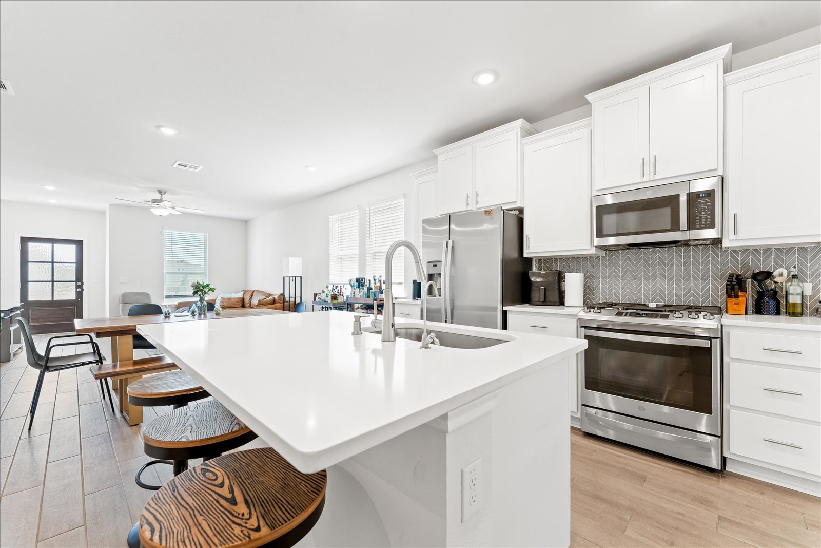 4607 Sweet Annie Path Austin, TX 78723 - Photo 10 of 29 Kitchen featuring stainless steel appliances, a breakfast bar, white cabinetry, light wood-style floors, and a kitchen island with sink
