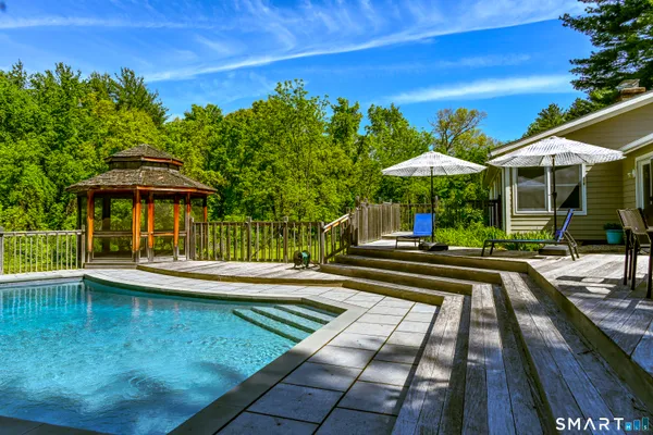 a view of swimming pool with chairs and umbrella