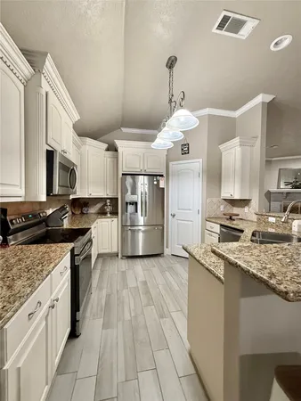 a kitchen with granite countertop a sink stove and refrigerator