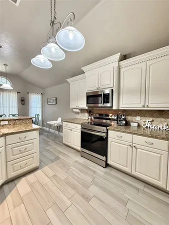 a kitchen with granite countertop a stove cabinets and stainless steel appliances