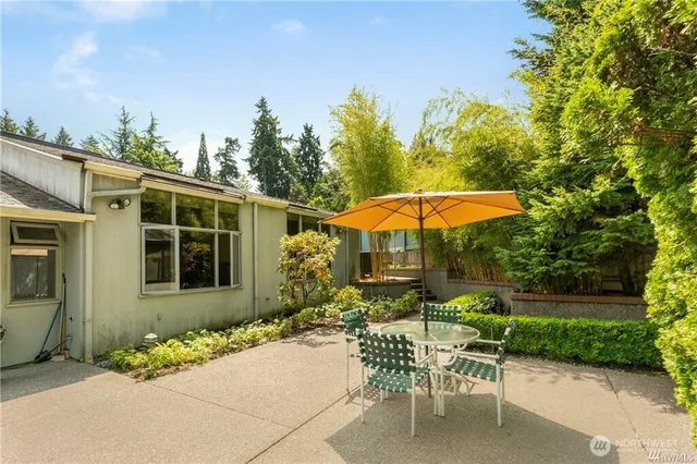a backyard of a house with table and chairs under an umbrella