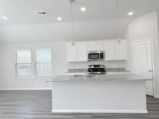 a kitchen with stainless steel appliances granite countertop a sink a stove and a microwave