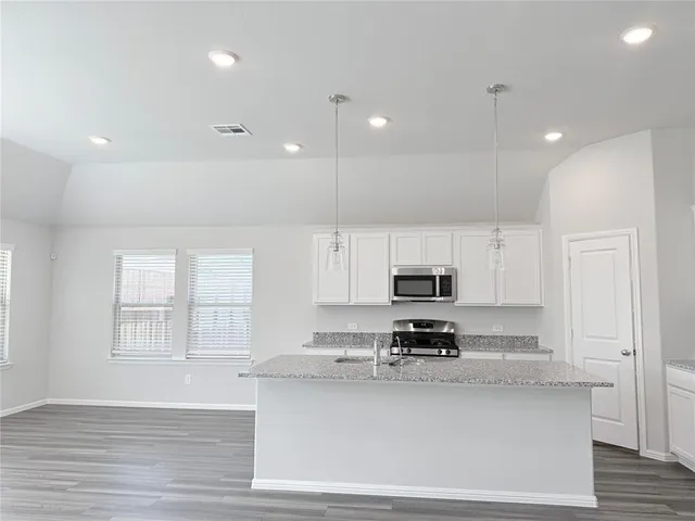 a kitchen with sink a microwave and cabinets