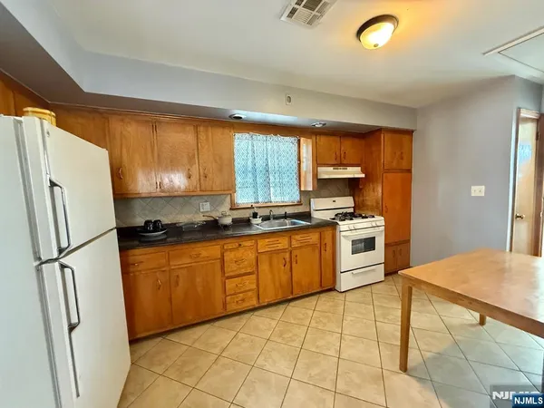 a kitchen with granite countertop a refrigerator stove top oven and sink