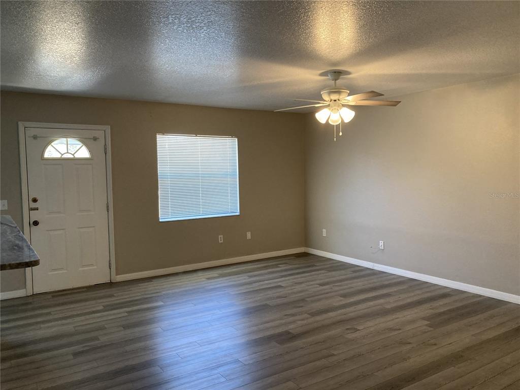 1088 Nomad Road Punta Gorda, FL 33983 - Photo 2 of 13 an empty room with wooden floor chandelier fan and windows