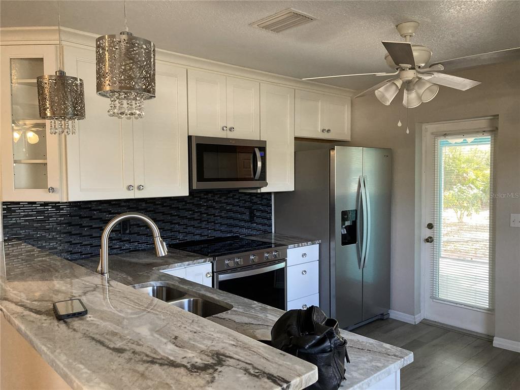 1088 Nomad Road Punta Gorda, FL 33983 - Photo 4 of 13 a kitchen with granite countertop a sink stainless steel appliances and cabinets