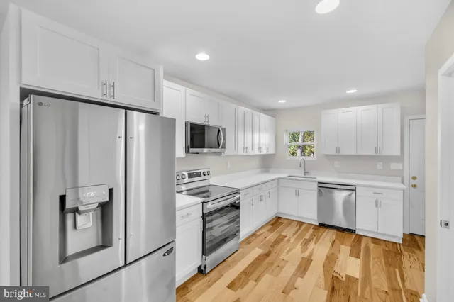 a kitchen with stainless steel appliances granite countertop a refrigerator sink and white cabinets