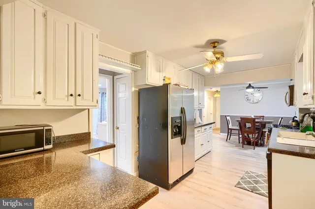 a kitchen with stainless steel appliances granite countertop a refrigerator a stove and white cabinets with wooden floor