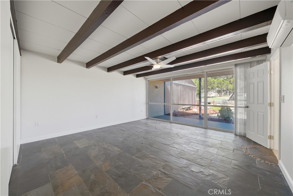 600 Gibbel Road Hemet, CA 92543 - Photo 13 of 28 Front bedroom freshly painted w slate flooring, floor to ceiling windows looking out to front yard and community greenbelt w beamed ceiling and new ceiling fan/light fixture.