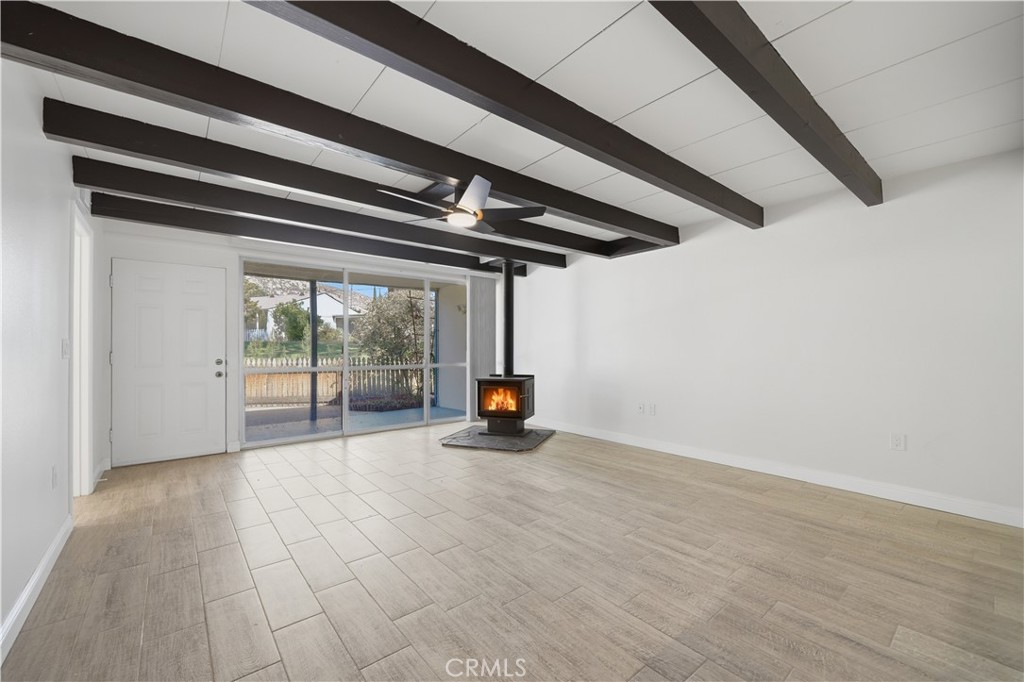600 Gibbel Road Hemet, CA 92543 - Photo 8 of 28 Large living room w beamed ceiling, wood burning stove, all new tile plank flooring and floor to ceiling window looking out to front yard and community green belt
