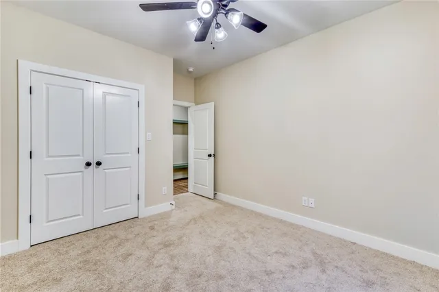 an empty room with a chandelier fan and closet